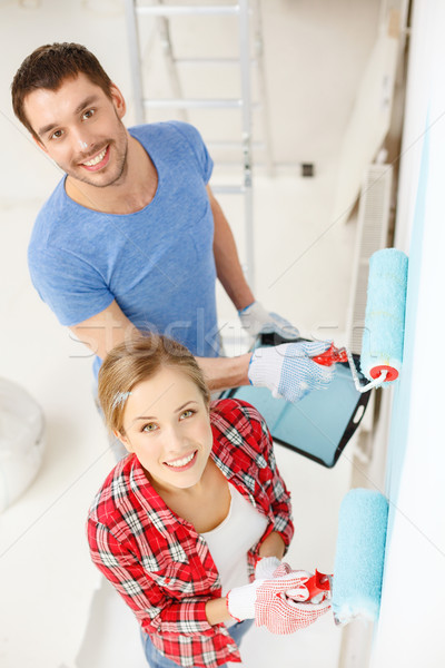 Stock photo: smiling couple painting wall at home