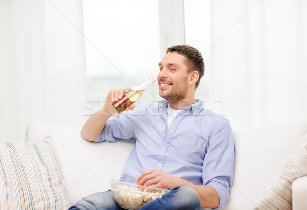 Sorridente homem cerveja pipoca casa tecnologia Foto stock © dolgachov