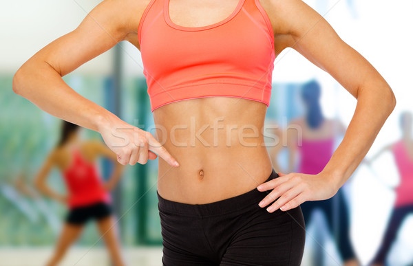 close up of woman pointing finger at her six pack Stock photo © dolgachov