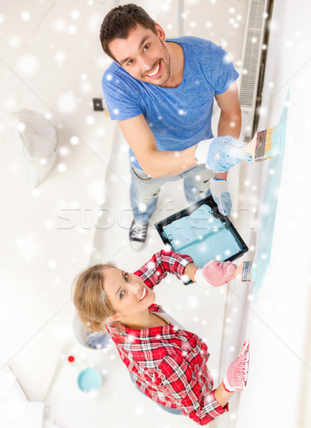 smiling couple with paintbrushes painting wall Stock photo © dolgachov