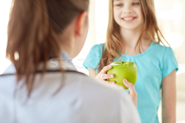 close up of doctor giving apple to happy girl Stock photo © dolgachov