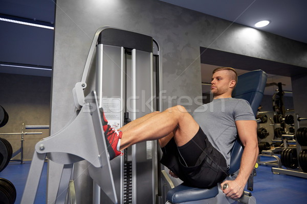 man flexing leg muscles on gym machine Stock photo © dolgachov