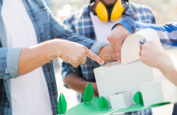 Stock photo: close up of builders with paper house model