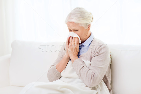 sick senior woman blowing nose to paper napkin Stock photo © dolgachov