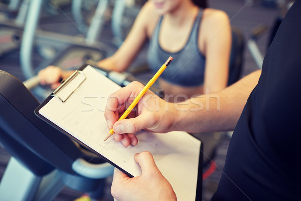 close up of trainer hands with clipboard in gym Stock photo © dolgachov