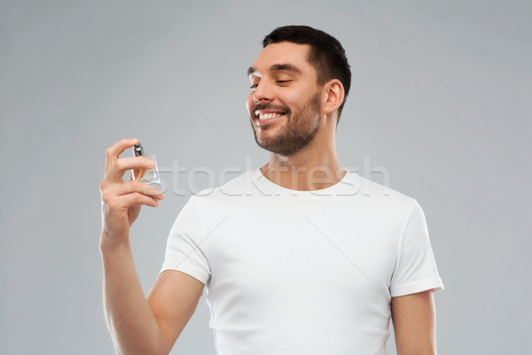 smiling man with male perfume over gray background Stock photo © dolgachov