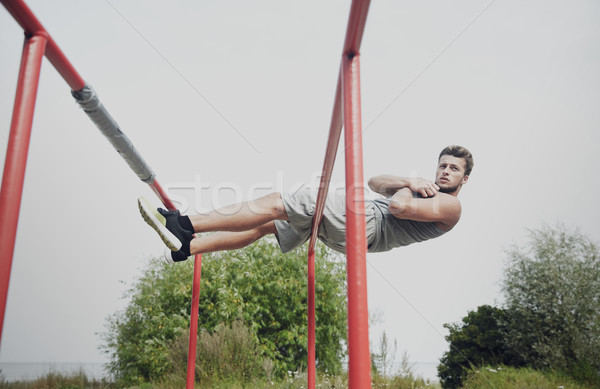 young man doing sit up on parallel bars outdoors Stock photo © dolgachov