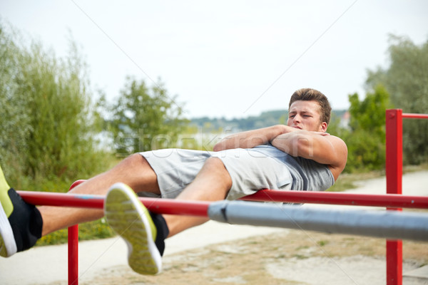 Junger Mann sitzen up parallel Bars Freien Stock foto © dolgachov