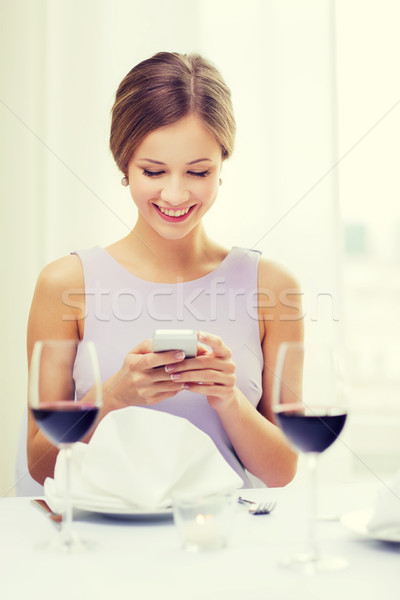 smiling woman with smartphone at resturant Stock photo © dolgachov