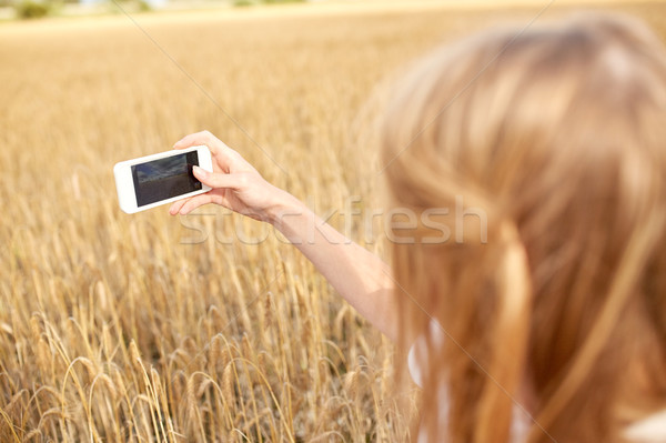 close up of girl with smartphone on cereal field Stock photo © dolgachov