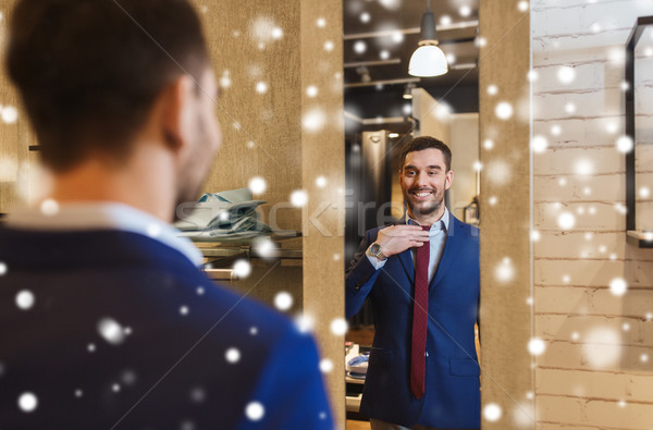 man trying tie on at mirror in clothing store Stock photo © dolgachov