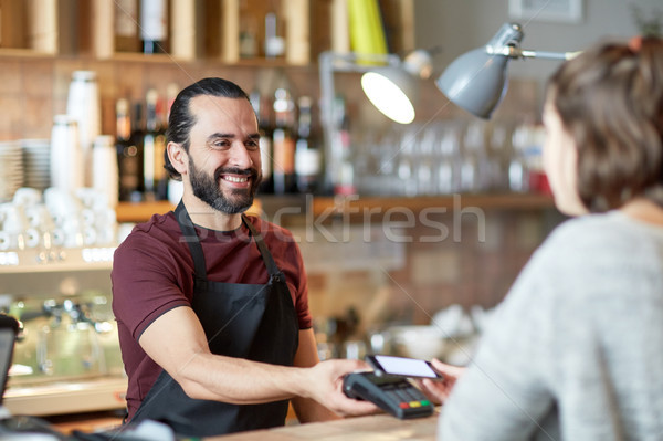 barman and woman with card reader and smartphone Stock photo © dolgachov