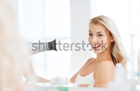 happy young woman with fan drying hair at bathroom Stock photo © dolgachov