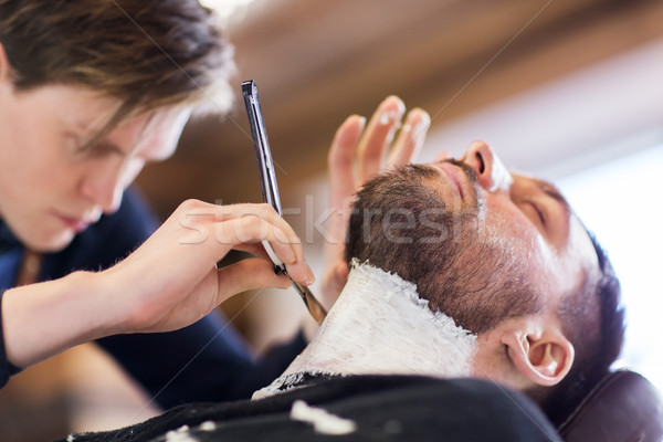 man and barber with straight razor shaving beard Stock photo © dolgachov