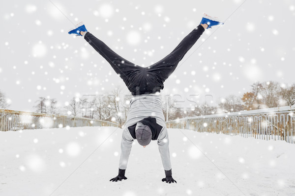 young man doing handstand in winter Stock photo © dolgachov