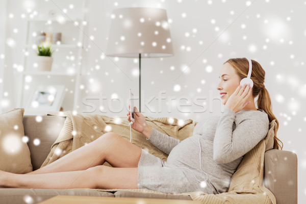 Stock photo: pregnant woman with smartphone and headphones