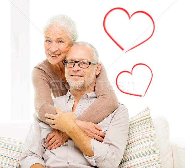 Stock photo: happy senior couple hugging on sofa at home