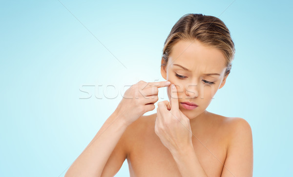 young woman squeezing pimple on her face Stock photo © dolgachov