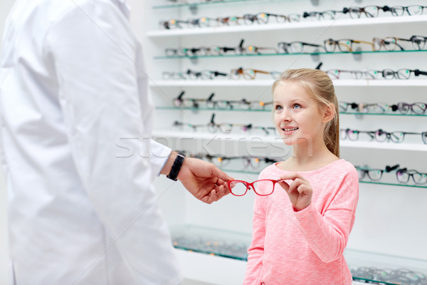 optician giving glasses to girl at optics store Stock photo © dolgachov