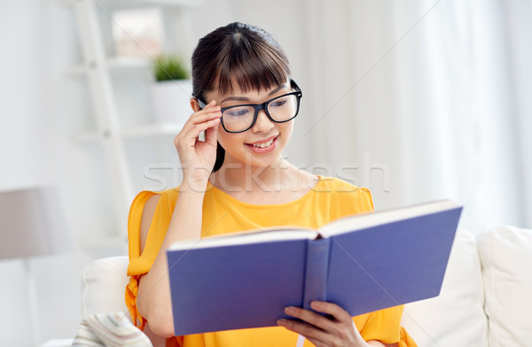 Stock photo: smiling young asian woman reading book at home