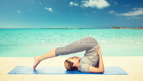 woman making yoga in plow pose on mat Stock photo © dolgachov