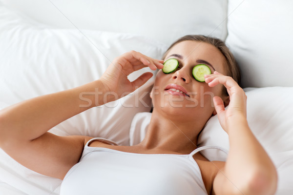 Stock photo: beautiful woman applying cucumbers to face at home