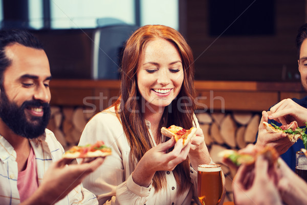 friends eating pizza with beer at restaurant Stock photo © dolgachov