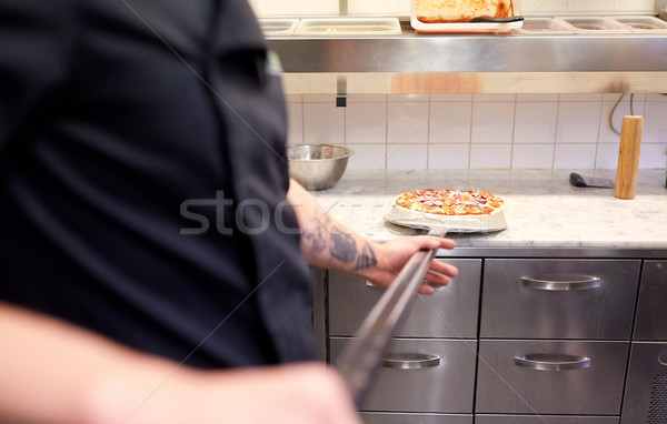 Stock photo: cook or baker with pizza on peel at pizzeria