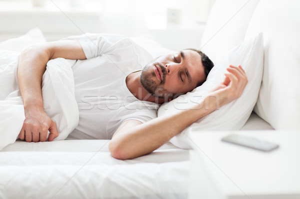 man sleeping in bed with smartphone on nightstand Stock photo © dolgachov