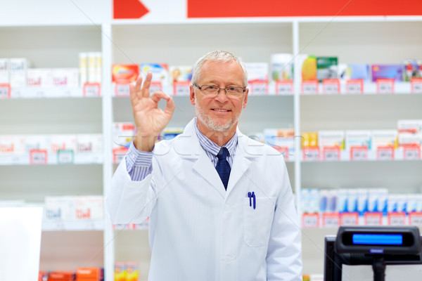 senior apothecary at pharmacy showing ok hand sign Stock photo © dolgachov