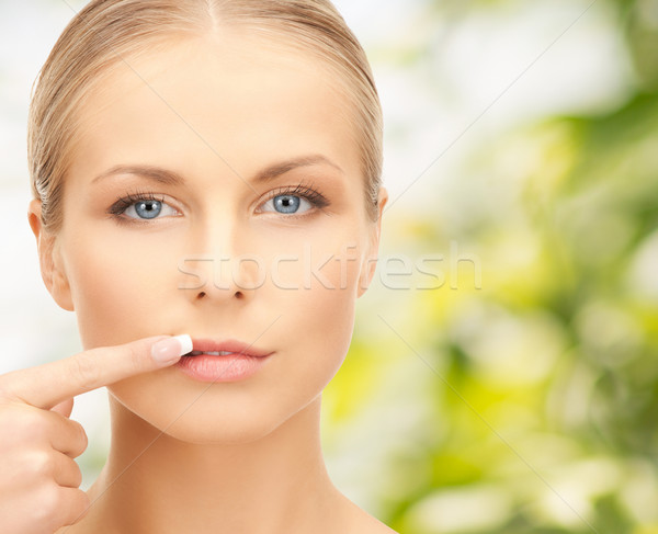 beautiful young woman pointing finger to her lips Stock photo © dolgachov