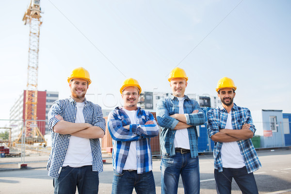 group of smiling builders in hardhats outdoors Stock photo © dolgachov