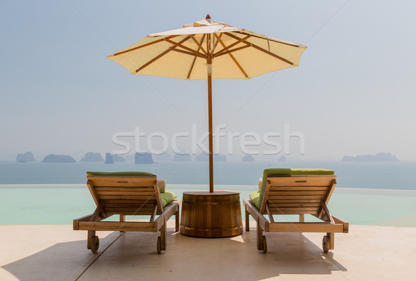 Stock photo: infinity pool with parasol and sun beds at seaside