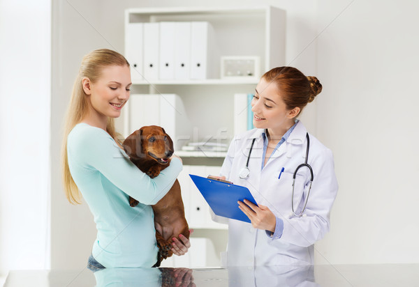 happy woman with dog and doctor at vet clinic Stock photo © dolgachov
