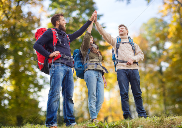 happy friends with backpacks making high five Stock photo © dolgachov