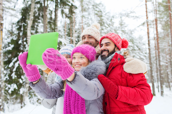 smiling friends with tablet pc in winter forest Stock photo © dolgachov