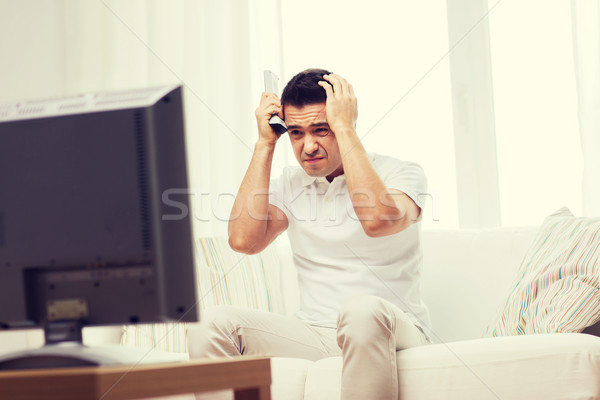 Stock photo: disappointed man watching tv at home