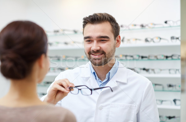 optician giving glasses to woman at optics store Stock photo © dolgachov