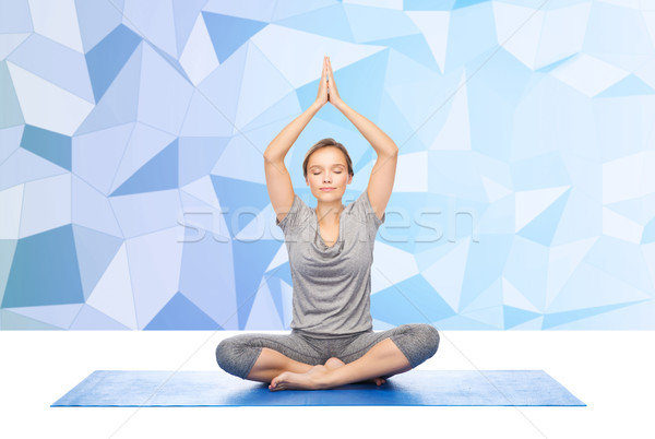 woman making yoga meditation in lotus pose on mat Stock photo © dolgachov