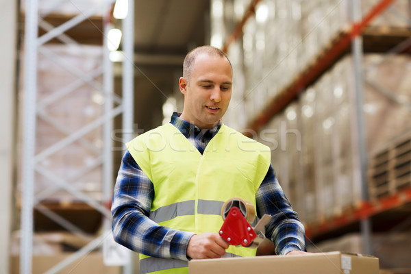 man in safety vest packing box at warehouse Stock photo © dolgachov