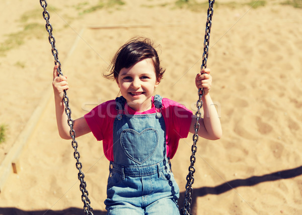 happy little girl swinging on swing at playground Stock photo © dolgachov