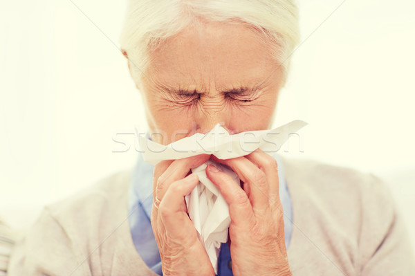 sick senior woman blowing nose to paper napkin Stock photo © dolgachov
