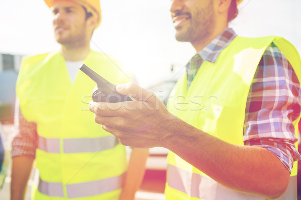 Stock photo: close up of builders in vests with walkie talkie