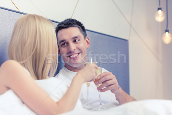 Stock photo: smiling couple with champagne glasses in bed
