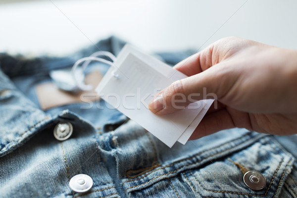 close up of hand holding price tag of denim jacket Stock photo © dolgachov