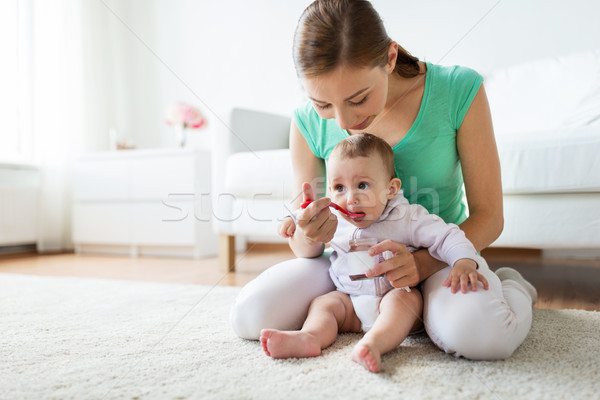 mother with spoon feeding little baby at home Stock photo © dolgachov