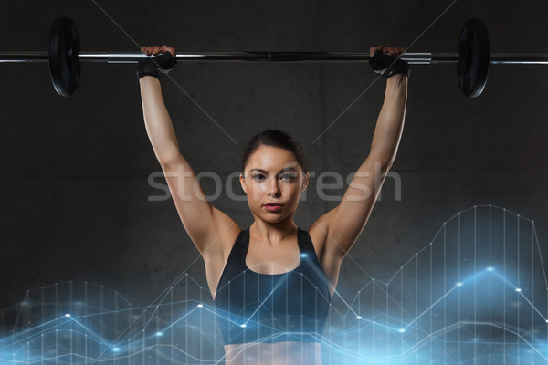 Stock photo: young woman flexing muscles with barbell in gym