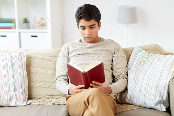 man sitting on sofa and reading book at home Stock photo © dolgachov