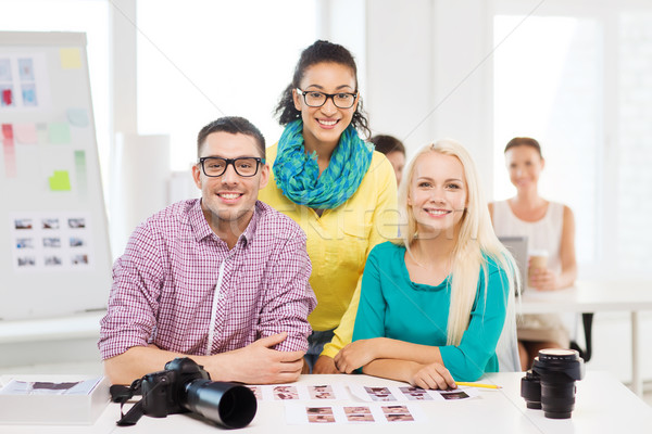 Stock photo: smiling team with printed photos working in office