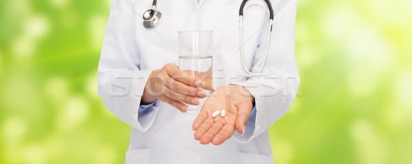 close up of doctor offering pills and water Stock photo © dolgachov